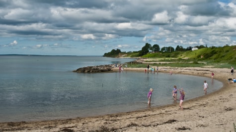 Sommerdag og børn nyder vandet ved Grønbjerggård strand