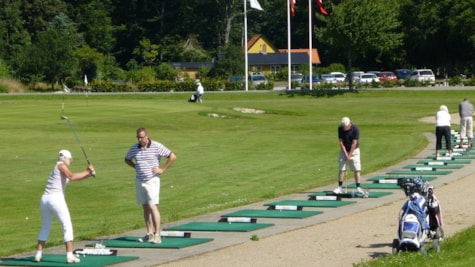 Golfspillere øver deres slag på golfbanen ved Bogense Golfklub