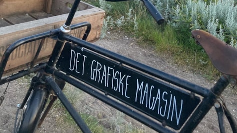 Gammeldags cykle med påskrevet logo fra Det Grafiske Magasin på hjarnø