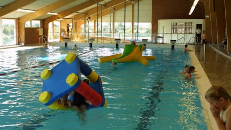 Børn leger i poolen i Bogense Svømmehal med udsigt til campingpladsen