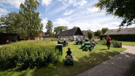 Besøgende sidder ved bord bænkesæt på græsplænen ved Gludmuseum