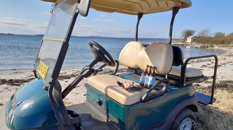 Ølflasker i golfbil som holder på stranden i solskinsvejr