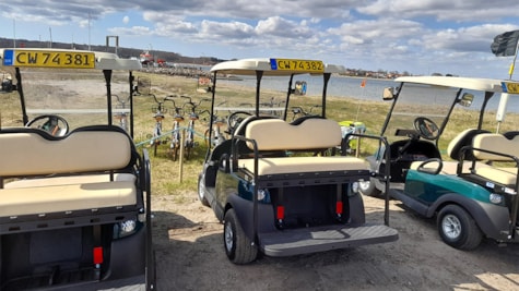 Tre golfbiler holder ved kysten Hjarnø Golfbil og Cykeludlejning